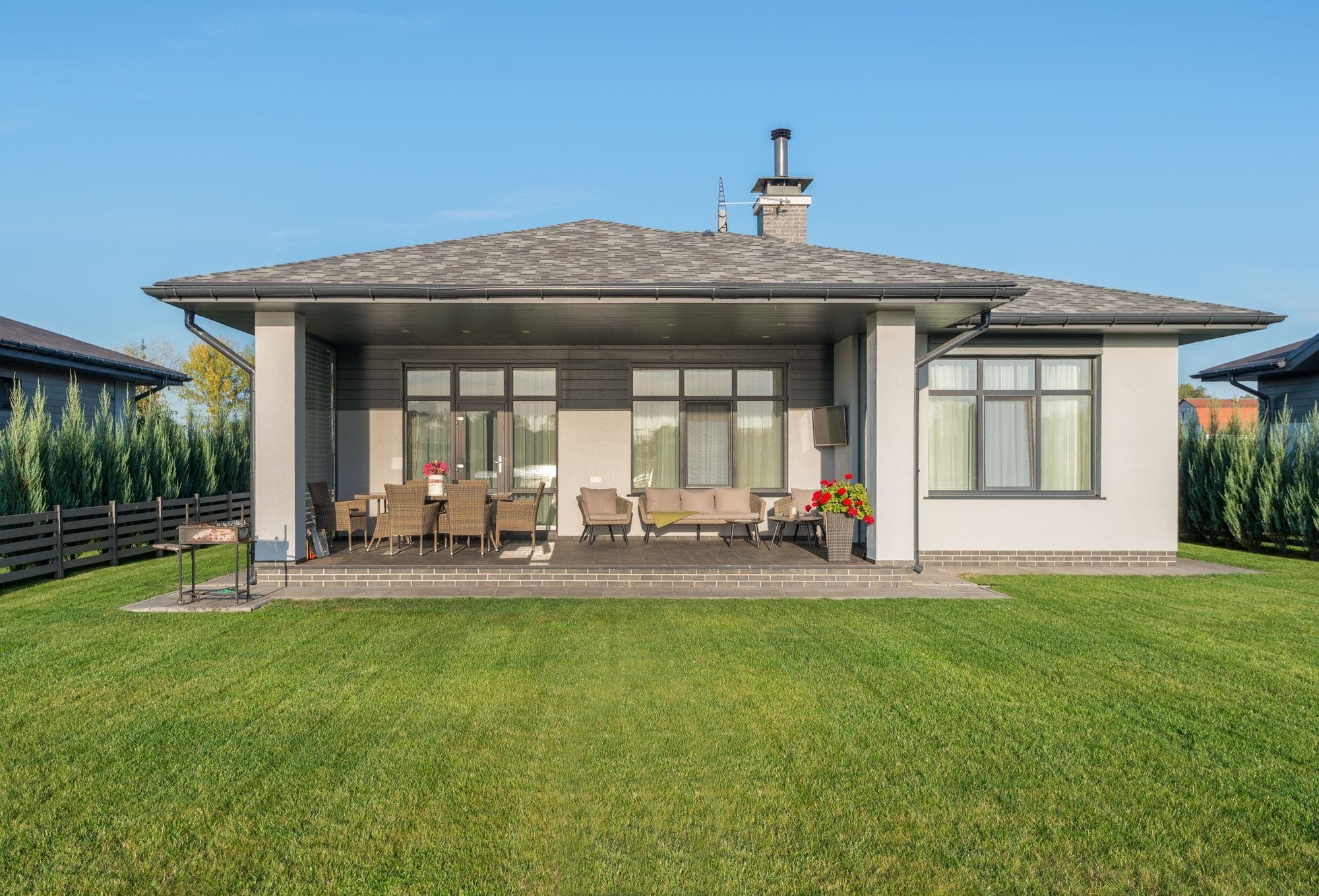 A covered patio and manicured lawn behind a contemporary home