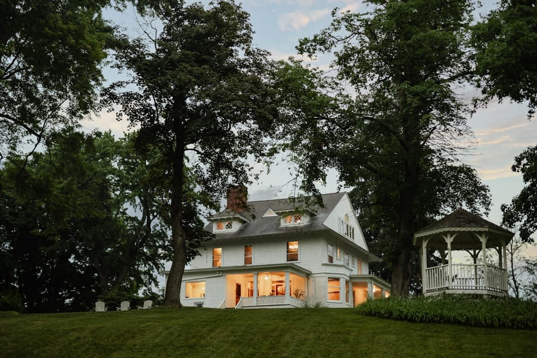 A white estate home lit up at dusk